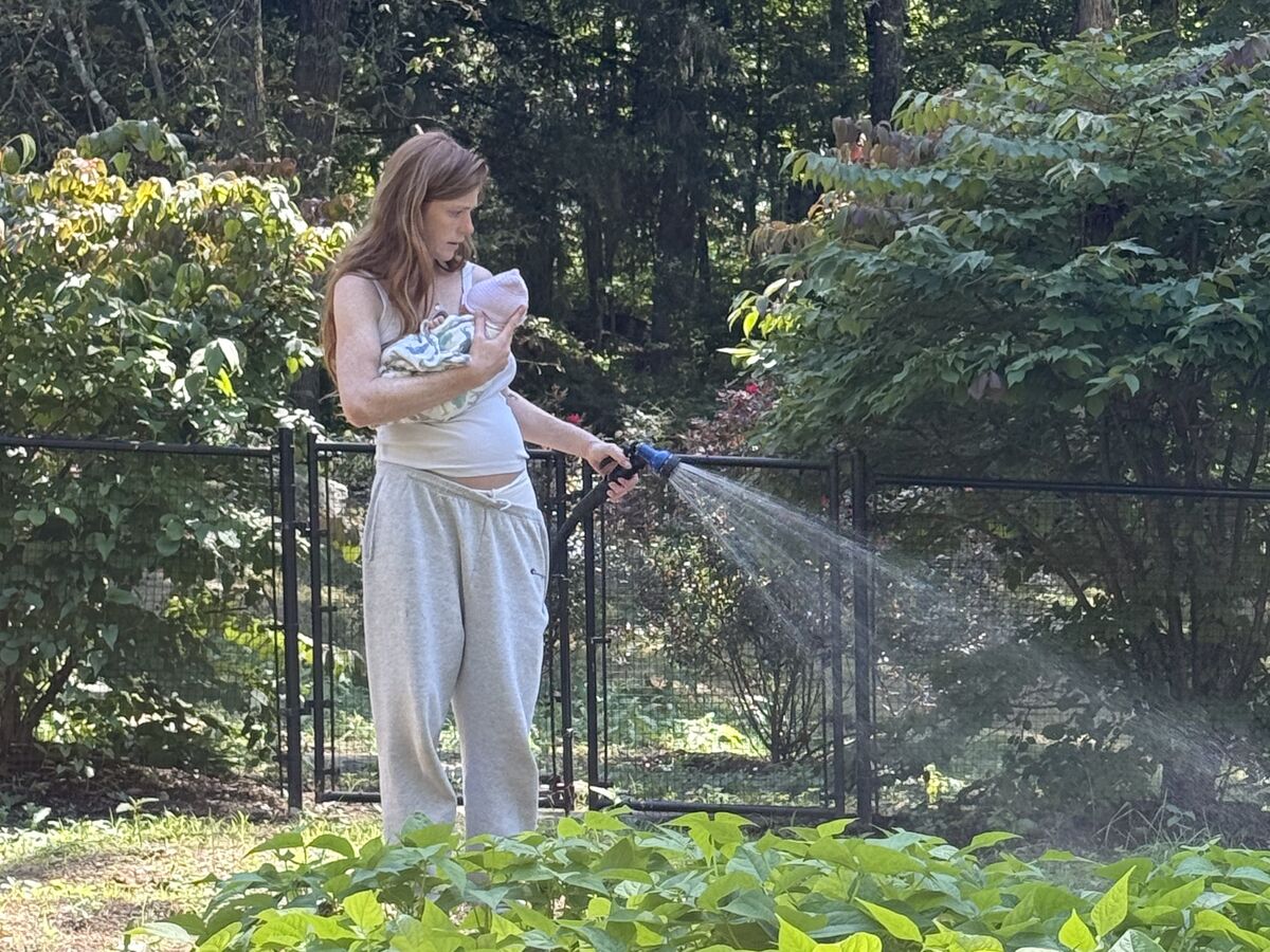 Watering the bean patch, baby in arm